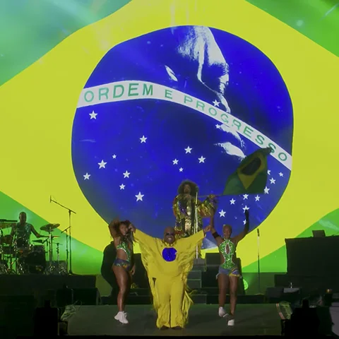 Ceelo Green com bandeira do Brasil ao fundo no painel de LED